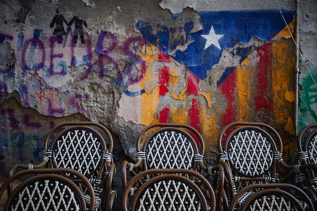 Sillas de mimbre ante pintura desconchada, una estrella y grafitis en Córcega