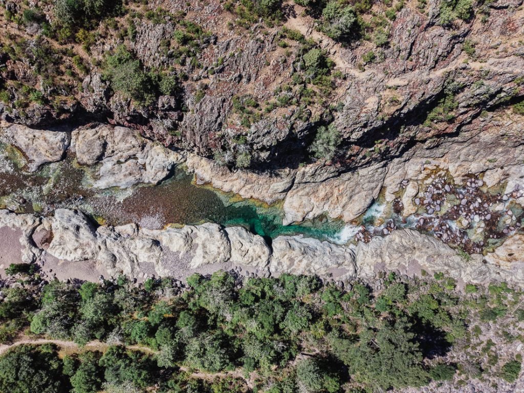 Agua verde y clara entre bloques de roca claros en el río, desde el aire, en Córcega