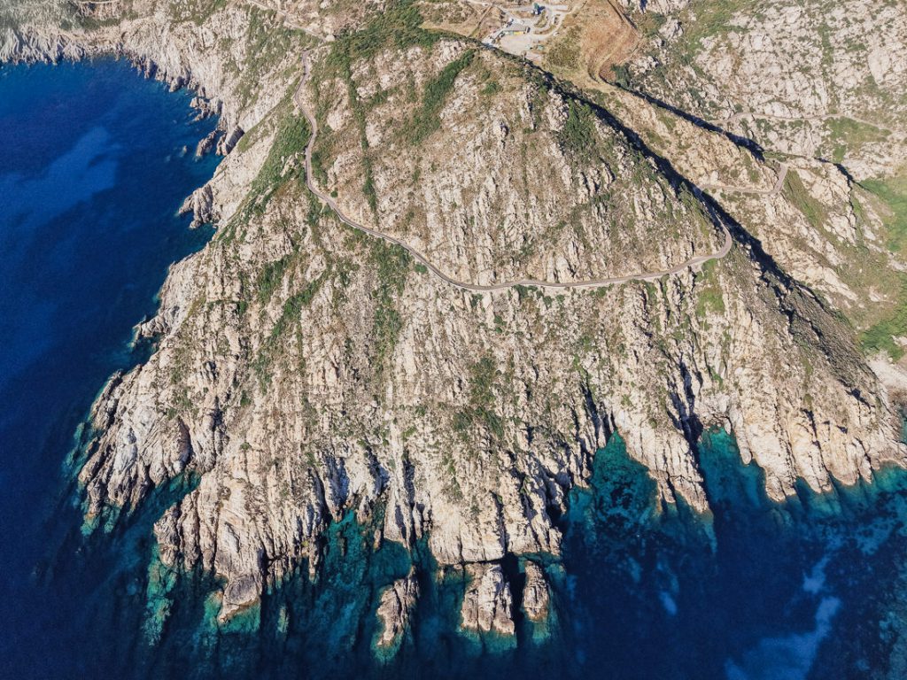 Curvas de una carretera sobre acantilados escarpados, desde el aire, en la costa de Córcega