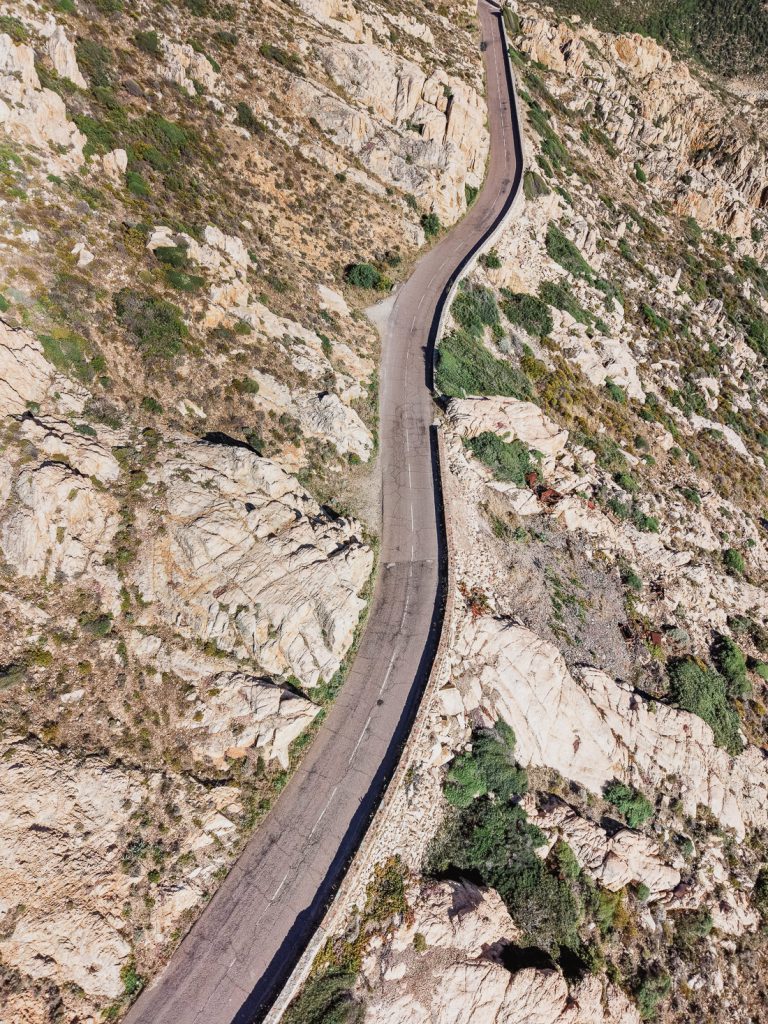 Curva cerrada de la carretera de montaña entre rocas claras, desde el aire, en Córcega