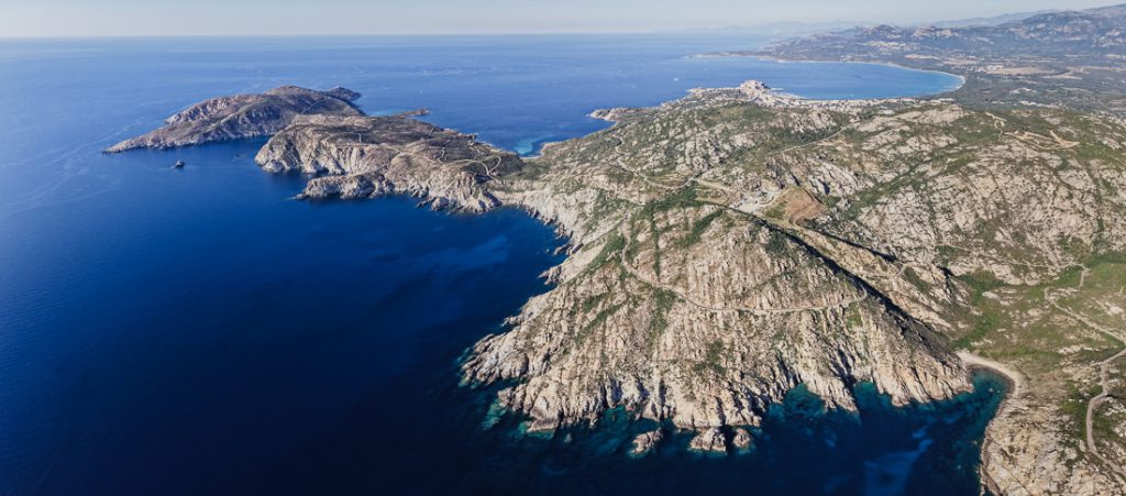 Cabos rocosos y bahías, con una larga línea de costa detrás, desde el aire, sobre Córcega