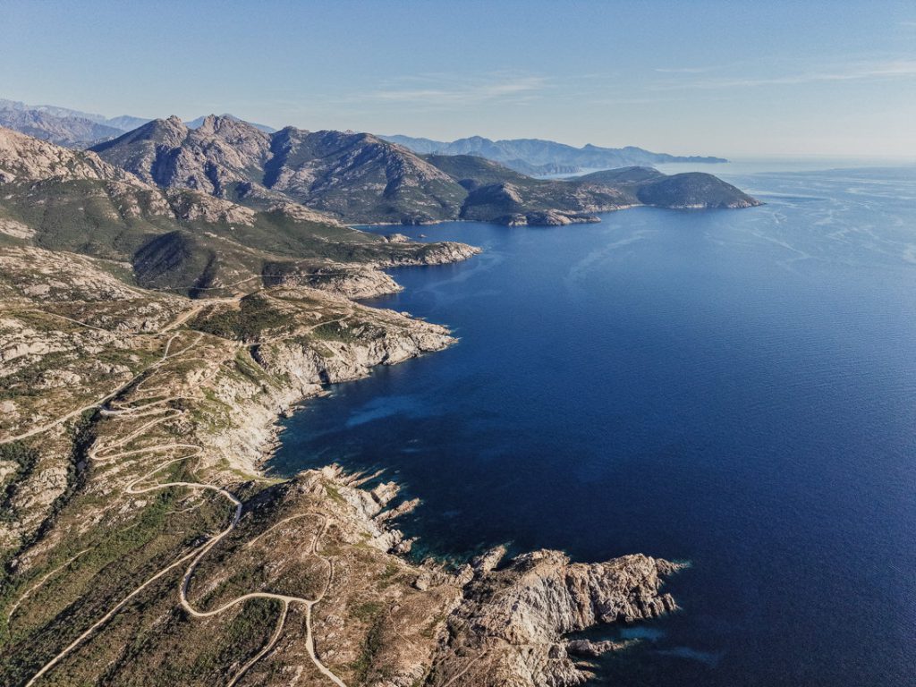 Muchas curvas de una carretera sobre la costa escarpada, desde el aire, en Córcega