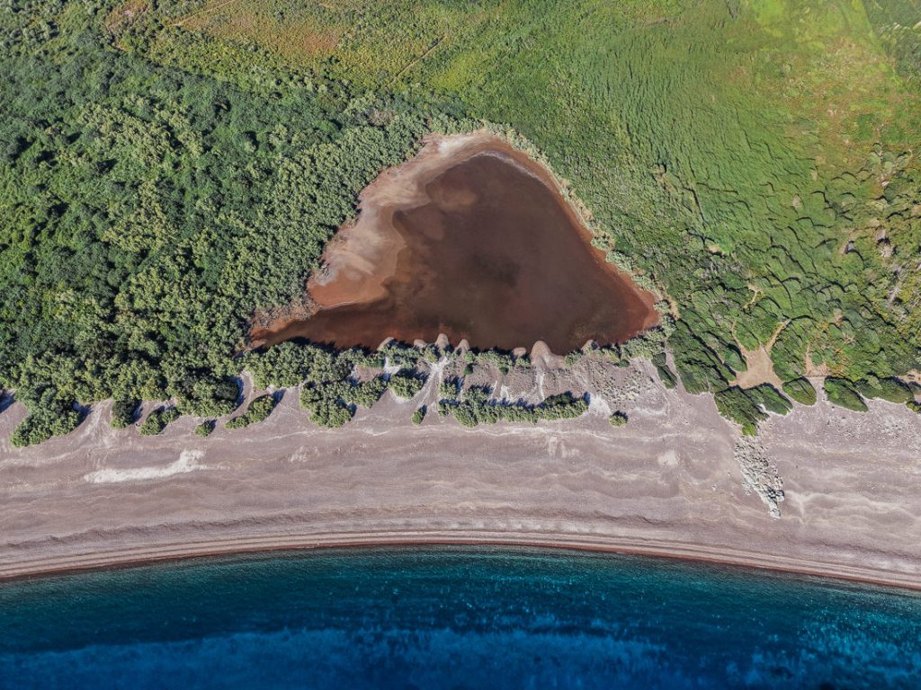 Laguna parduzca detrás de una playa de grava, desde el aire, en la costa de Córcega