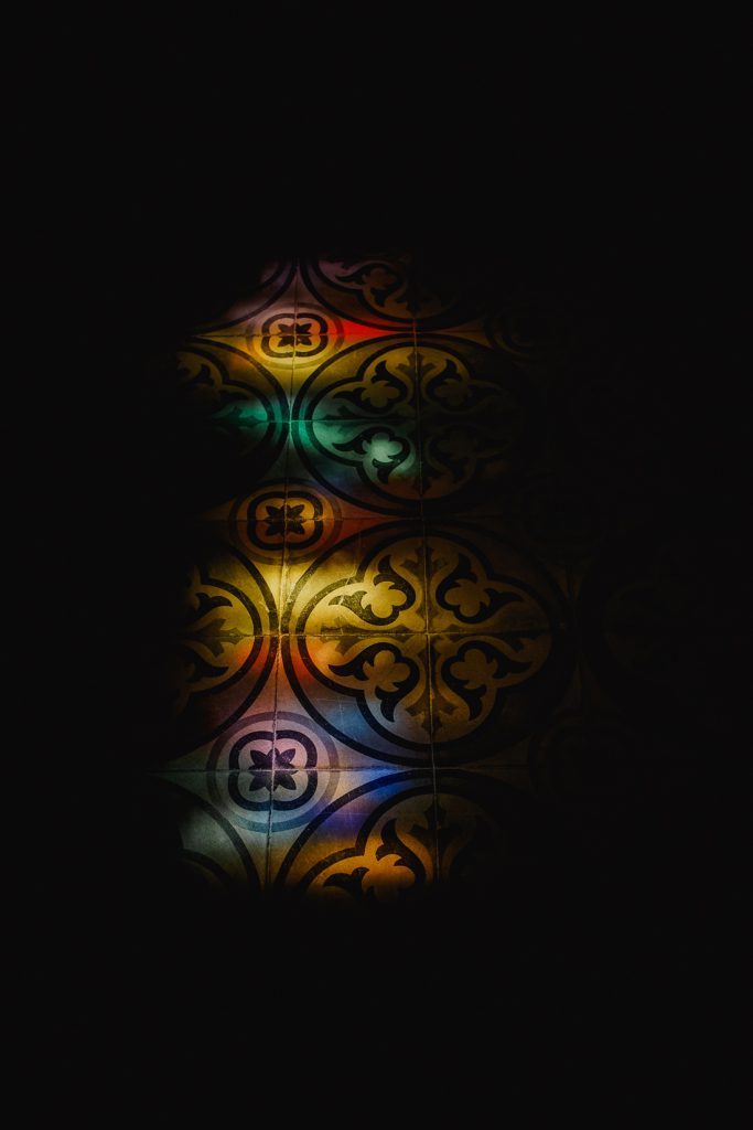 Vidriera ornamental de colores en la penumbra, solo un fragmento iluminado, en Córcega