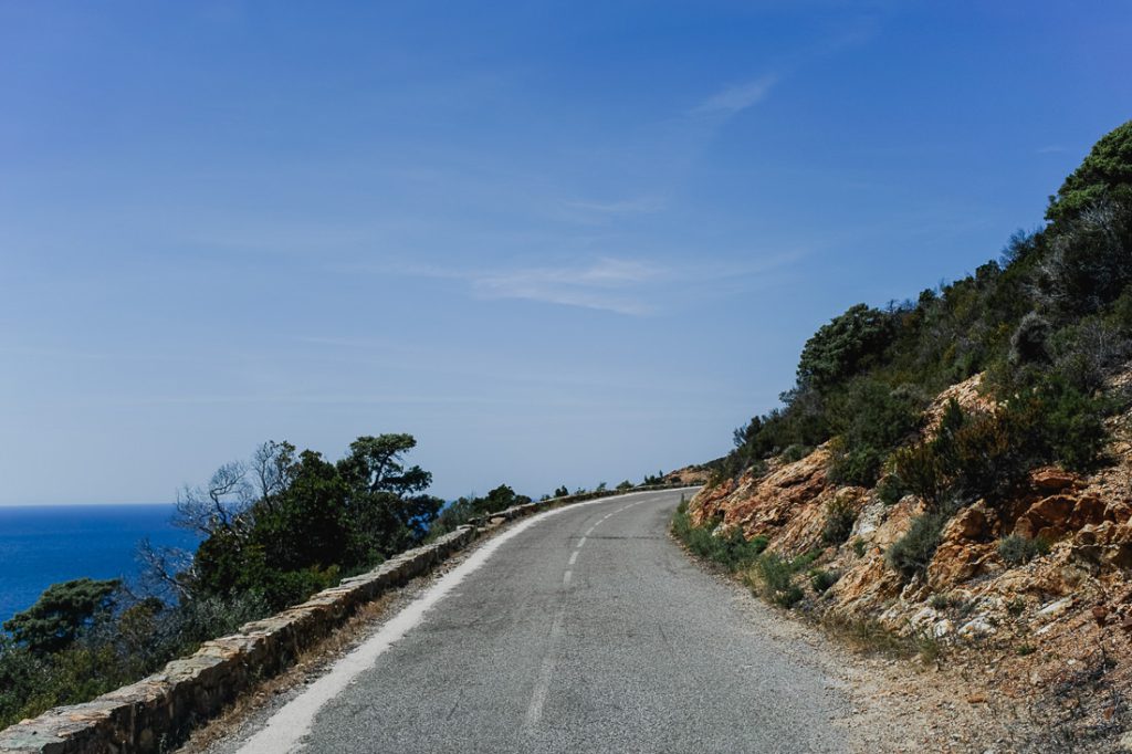 Curva de la carretera costera sobre el mar, con maquis en la ladera rocosa en Córcega