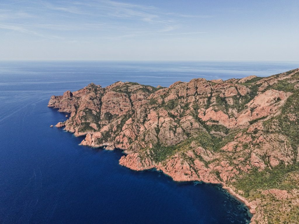 Costa de roca roja de las Calanques sobre el mar azul intenso, desde el aire, en Córcega