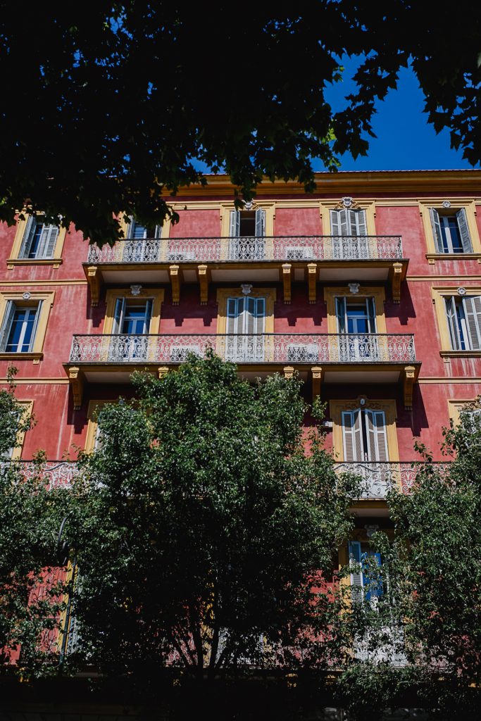Casa roja con marcos amarillos y balcones de hierro forjado en Córcega