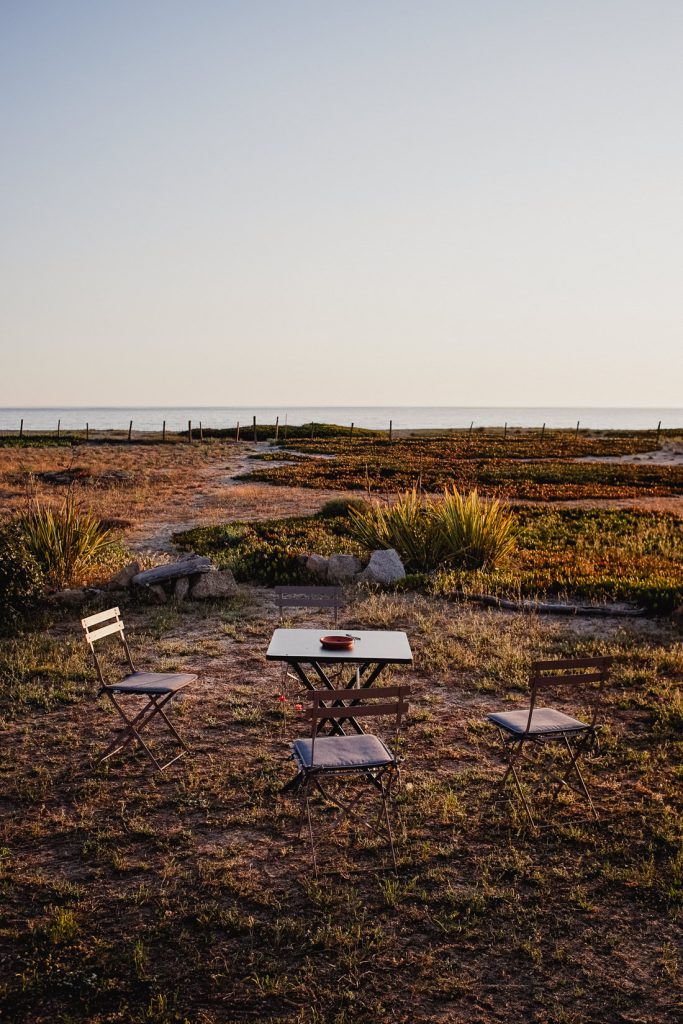 Mesa y sillas plegables sobre tierra seca junto al mar en Córcega