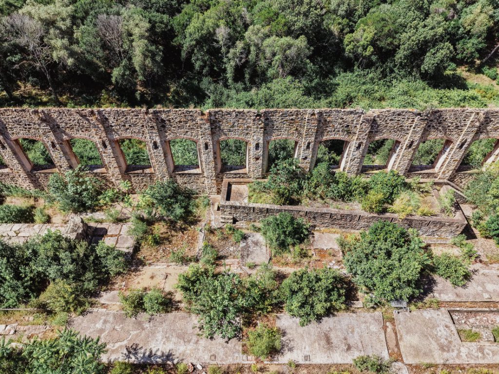Acueducto de piedra con arcos y arbustos entre los muros, desde el aire, en Córcega
