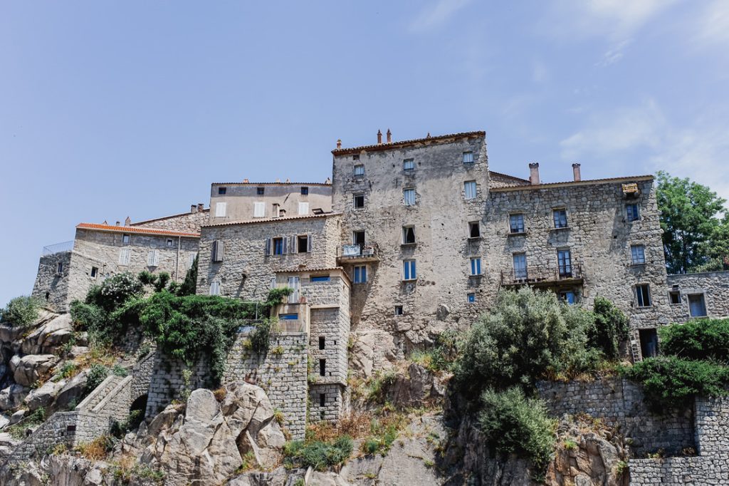 Casas de piedra escalonadas sobre una roca, con escaleras y pequeños balcones en Córcega