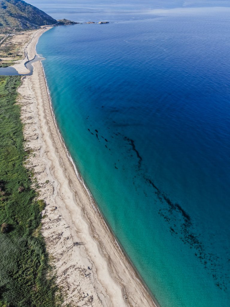 Larga playa de arena y agua turquesa, desde el aire, en la costa de Córcega